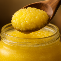 Jar of pure ghee spread with a wooden spoon and a flatbread being spread with it.